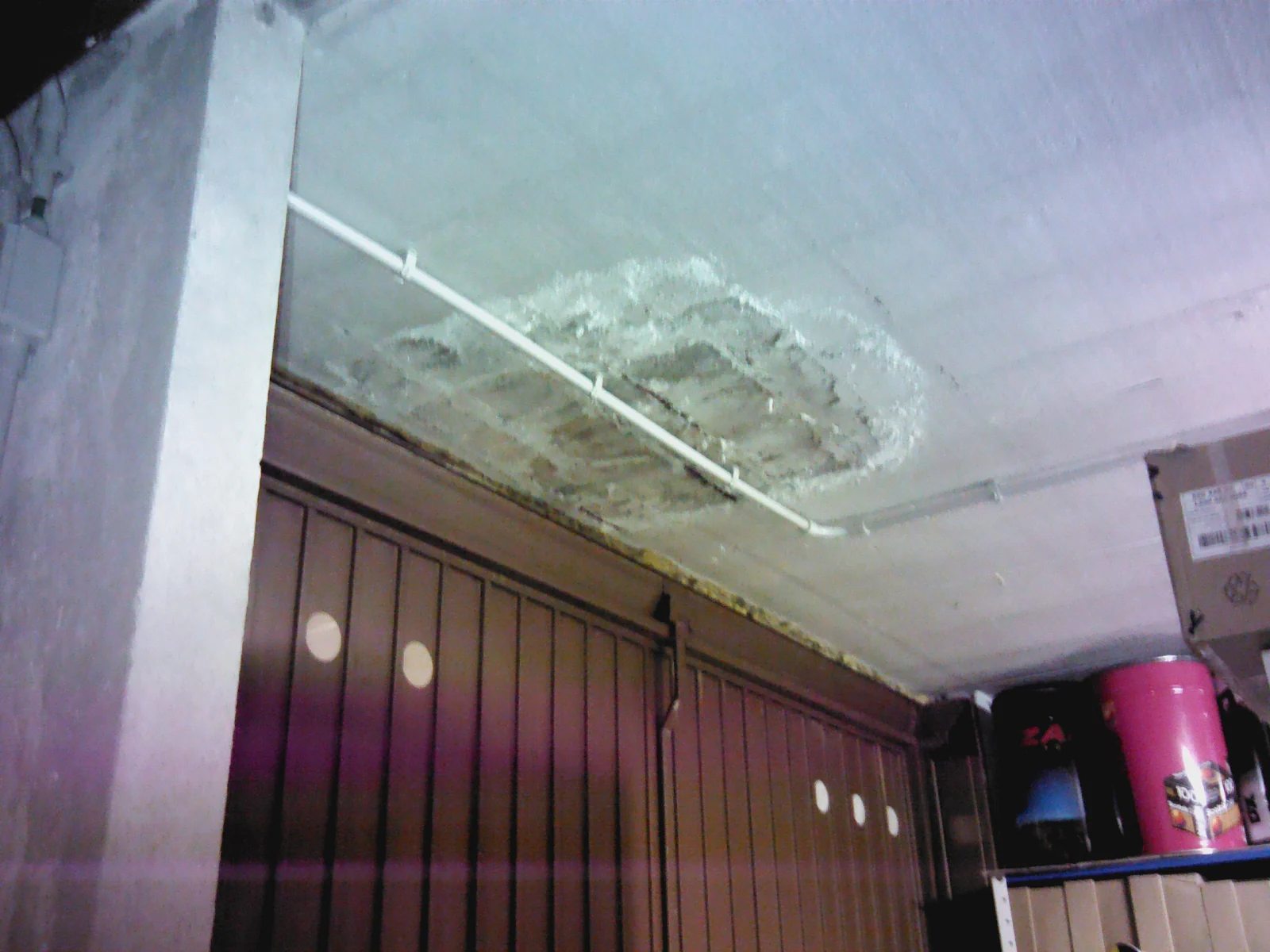 Soffitto di un box interrato con l'intonaco distaccato attorno a una macchia d'acqua.