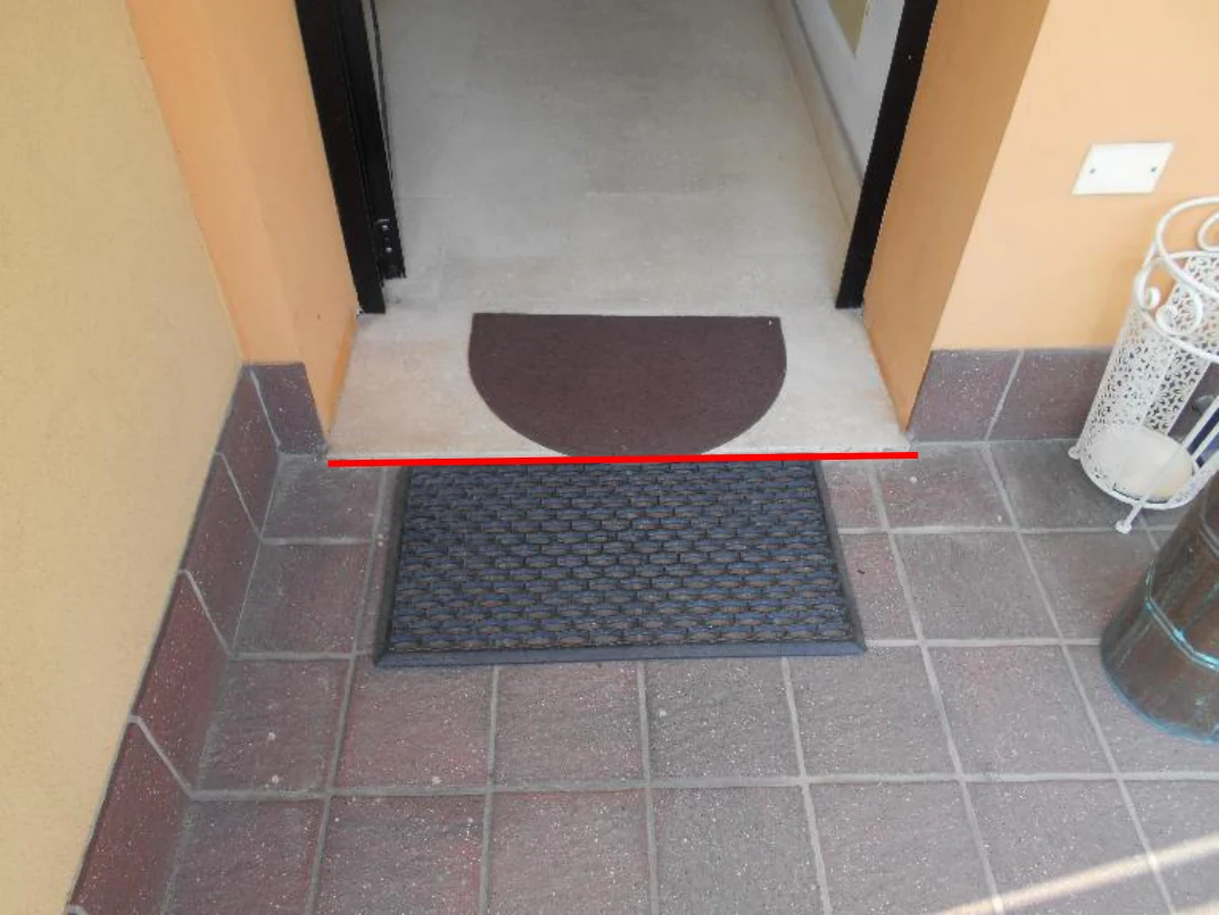 Soglia di accesso al fabbricato, con la linea di intersezione con il vialetto segnata in rosso.