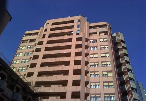 Facciata di un condominio alto vista dal basso, con i balconi e i pannelli di rivestimento